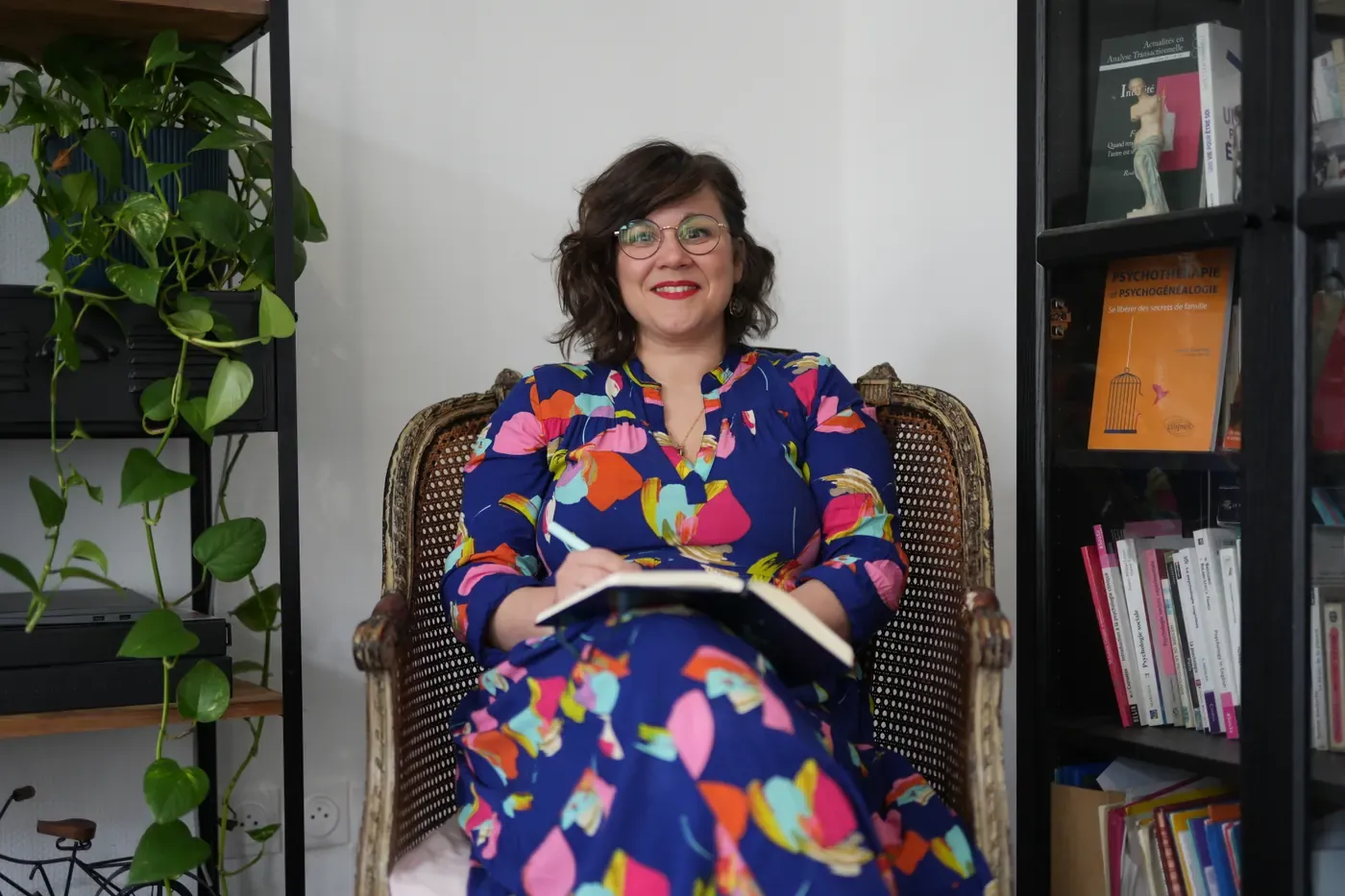 Julie Eggenspieler souriante, assise dans son fauteuil du cabinet, un carnet sur les genoux