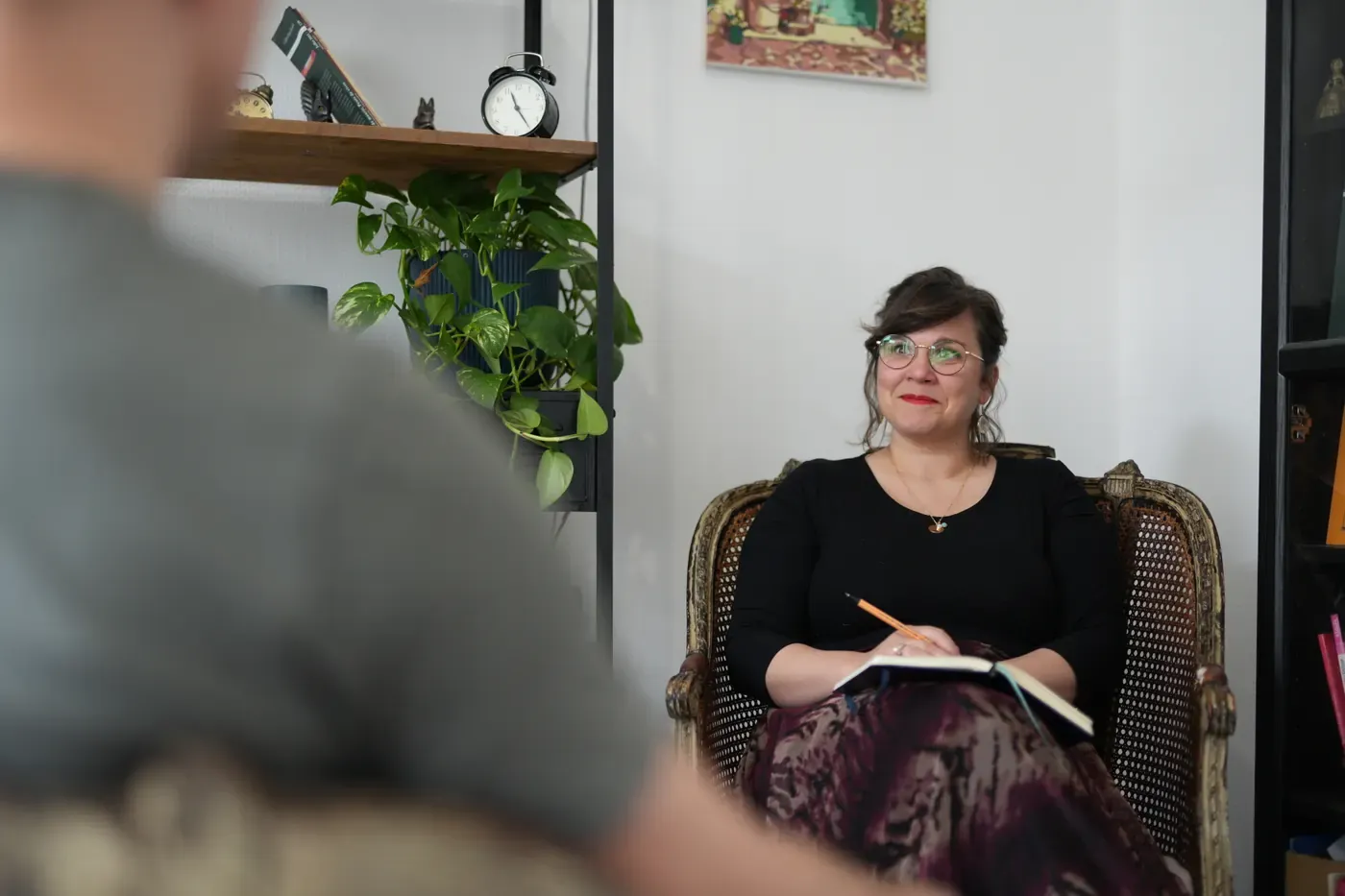 Julie Eggenspieler en séance, carnet et crayon en main, vue par-dessus l'épaule d'une personne
